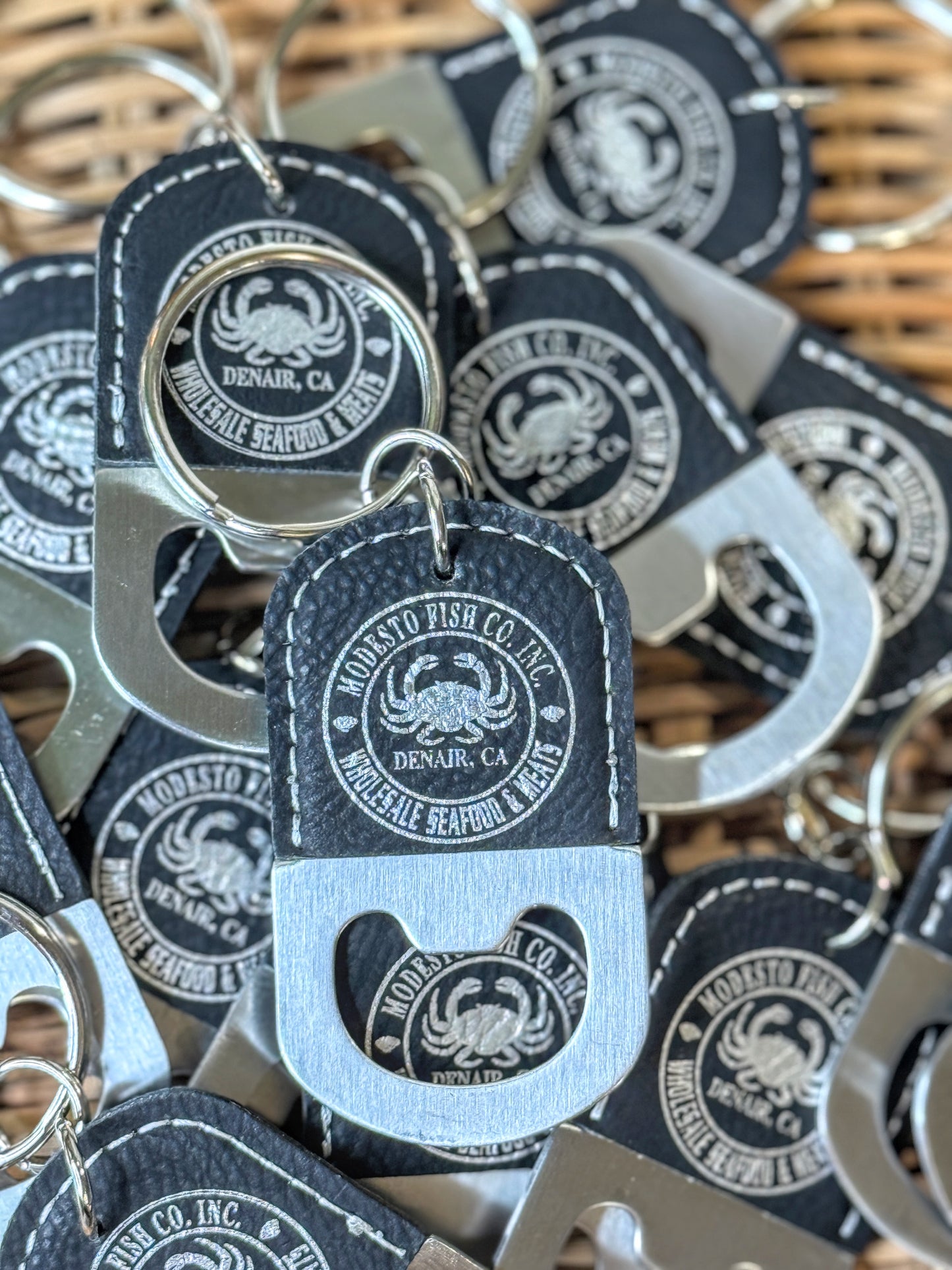 Custom laser engraved black vegan leatherette bottle opener keychain with silver engraved circular logo — personalized corporate gift by The Burn Shack, Denair CA