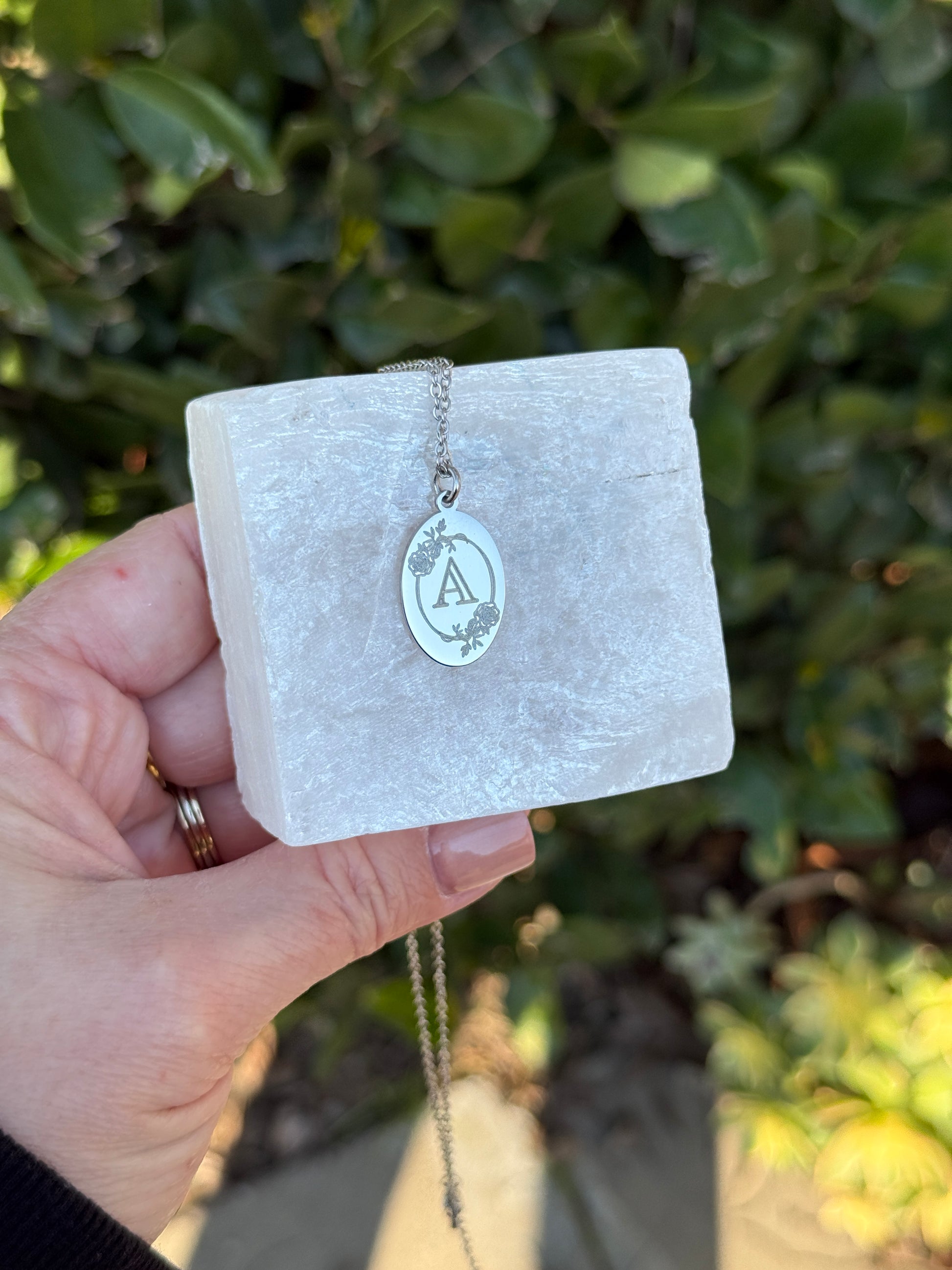 Oval charm necklace layered with other jewelry